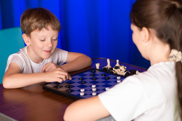 Children boy and girl playing a board game called Checkers