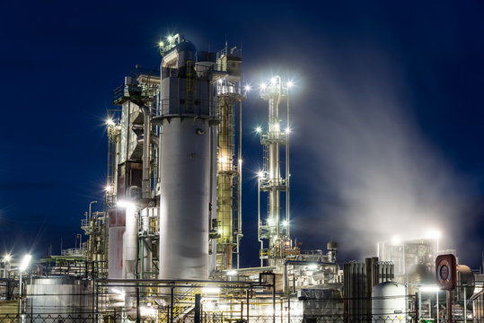 Ölraffinerie mit Rohren, Kolonnen und Lichtern in Speyer in Rheinland-Pfalz bei Nacht	