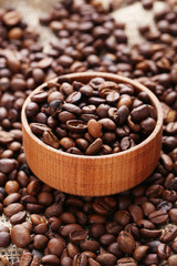 Coffee beans in bowl on a sack, close up
