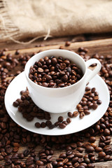 Coffee beans in cup on a brown wooden background