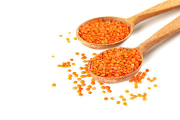 Red lentils in the wooden spoons on a white background