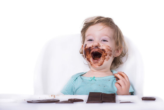 Adorable kid eating chocolate with face covered in chocolate