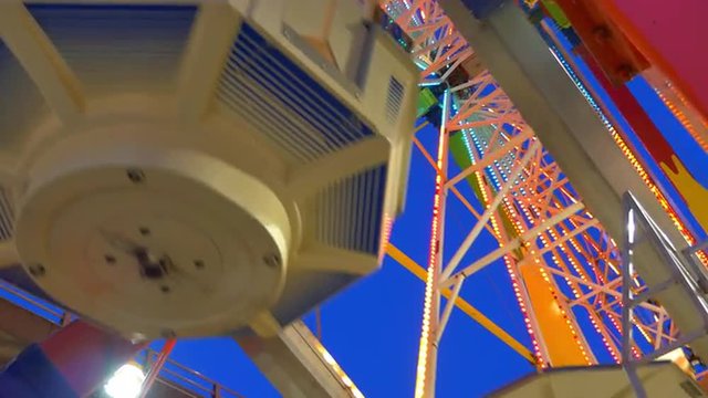 View from below of a carnival ride operating at night, with colorful lights