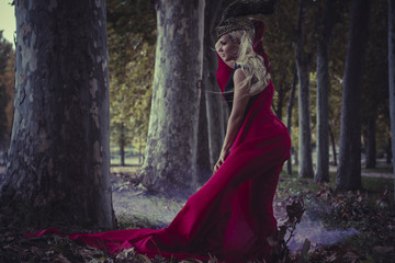 beautiful blond woman with red cape to the wind in a forest, rom