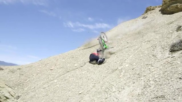 Mountain bike crash,  guy jumping from rocky ledge and crashing rolling down hill, slow motion.