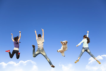 happy young group jumping together with dog