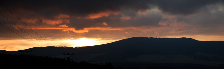 Panorama sunset over the mountains to the overcast sky.