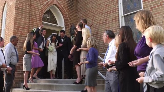 Slow-motion of guests throwing rice over a newlywed couple.