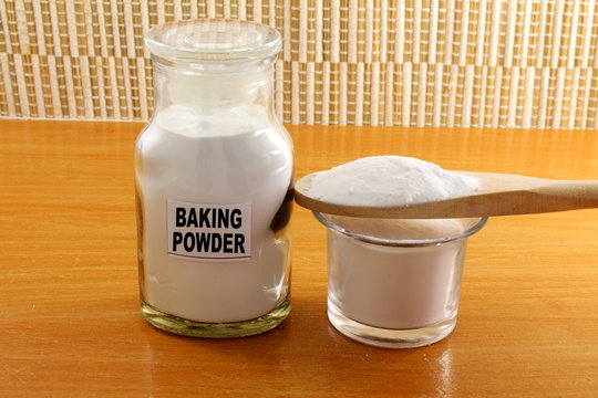 baking powder in bottle jar and wooden spoon