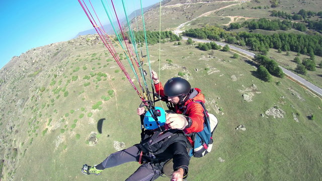 Paraglider paragliding over a green landscape, 