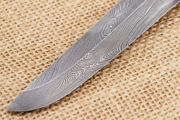 Fragment of the traditional handmade Finnish knife blade with the abstract wave pattern of damascus...