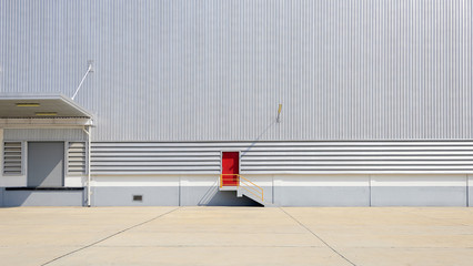 the sheet metal factory wall with the red door entrance