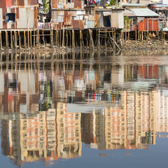 Views of the city's Slums from river. In water reflection of the new high-rise buildings. Ho Chi Minh City, Vietnam.
