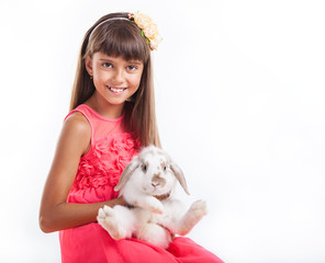 Young girl holding flap-eared rabbit against white