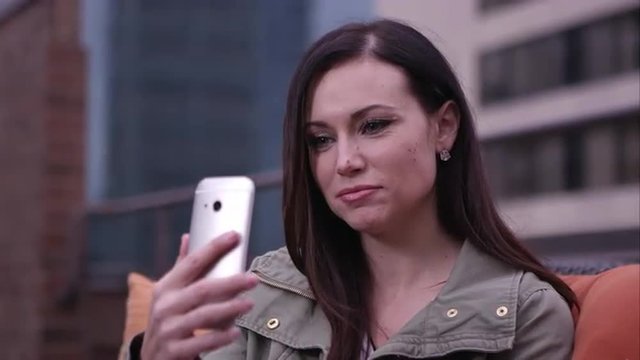 Woman laughing as she tries to take a selfie.