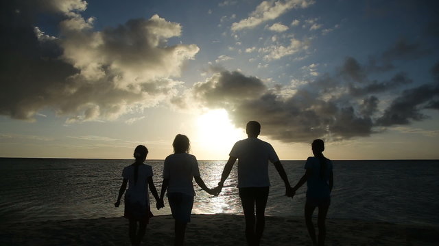 silhouette of family on the beach at sunset