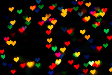 Fototapeta na wymiar beautiful bokeh made of warm blurred lights in the form of hearts on dark background