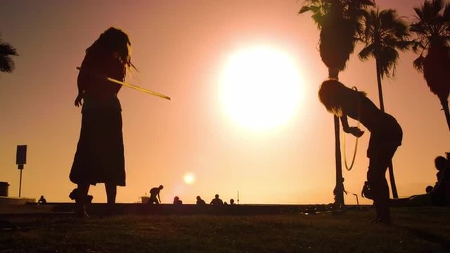Women play with hula hoops filmed in slow motion and with lens flare near Venice Beach, California
