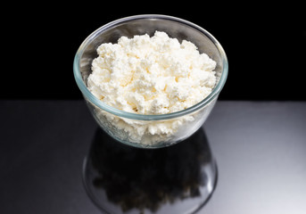 Cottage cheese in glass bowl on a dark background