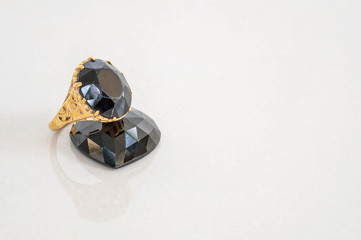 Closeup beautiful black jasper ring with black jasper in heart shape on blurred gray marble stone floor texture background