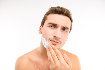 A young handsome man shaves in front of camera