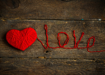 Red heart shape ewith an inscription love made from wool on old