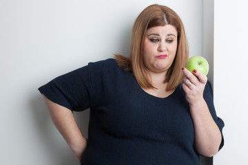 skeptical overweight woman holding an apple