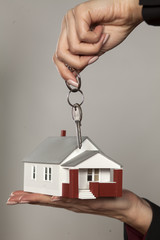 female hands holding a model house and keys