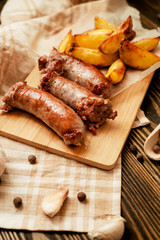 meat with vegetables , fried homemade sausage with roasted potatoes with garlic and pepper on a wooden background