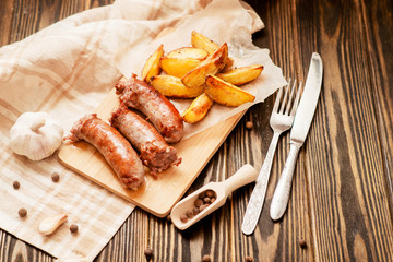 meat with vegetables , fried homemade sausage with roasted potatoes with garlic and pepper on a wooden background