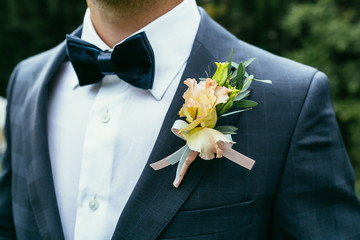 wedding boutonniere on chequered suit of groom with bow-tie