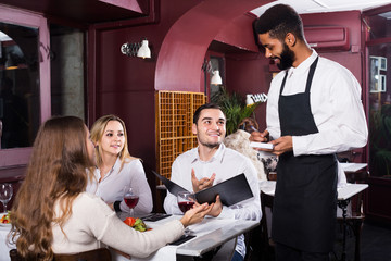 waiter taking care of adults at cafe table