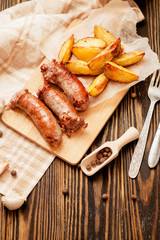 meat with vegetables , fried homemade sausage with roasted potatoes with garlic and pepper on a wooden background