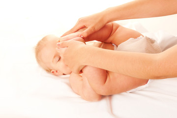 Fototapeta na wymiar Baby massage. Baby feet touching his forehead.