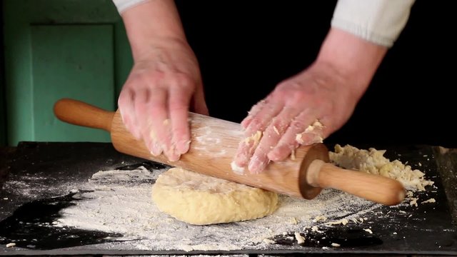 Female hands making dough for pasta over black table