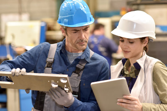Metallurgy workers in workshop using digital tablet