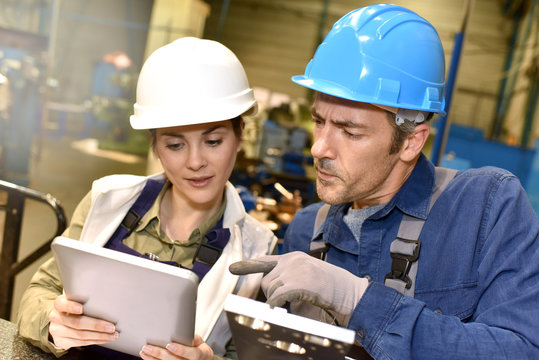 Metallurgy workers in workshop using digital tablet