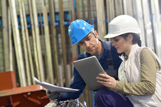 Engineers in metallurgy warehouse using digital tablet