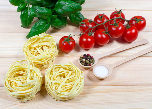 Raw homemade pasta and ingredients for pasta with tomatoes and basil.