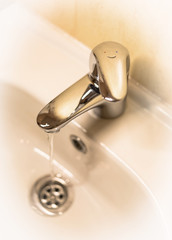 Snapshot type faucet and sink close-up in sepia.