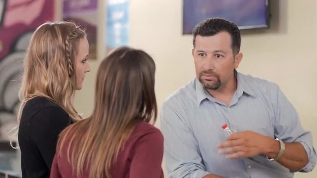 An associate at a recreational marijuana shop talking to female customers about a product
