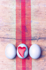 Ostereier mit Herz Herzmotiv auf Holzuntergrund mit Seidenbändern