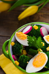 Broccoli salad with tulip flowers on wooden background.