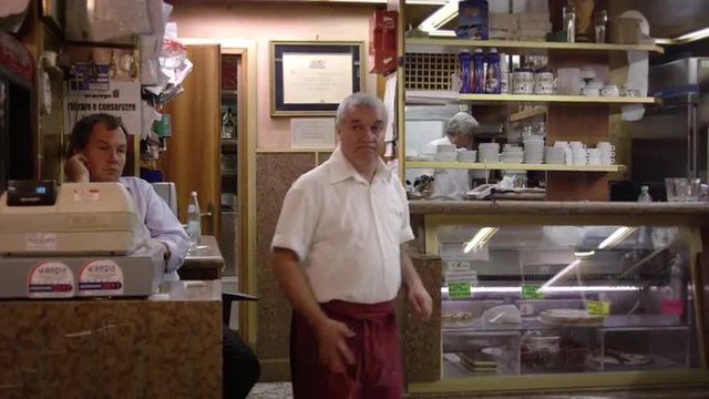 Static slow shot of three men working in an Italian cafe.