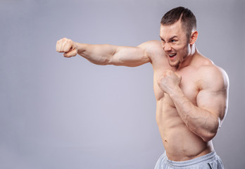 Fototapeta na wymiar Male boxer making training punches on grey background