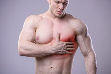 Fototapeta premium Athletic muscular man has pain in the heart. Red spot of injury