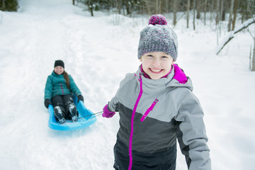 Fototapeta na wymiar Children Pulling Sledge Through Snowy Landscape