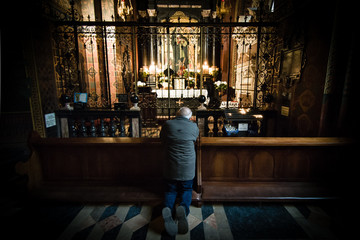 An old man prays in a church
