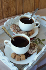 Two cups of coffee and cakes on a tray..