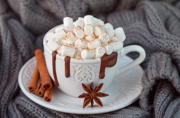 White mug with hot chocolate, marshmallows and cinnamon on wooden table. Rustic style
